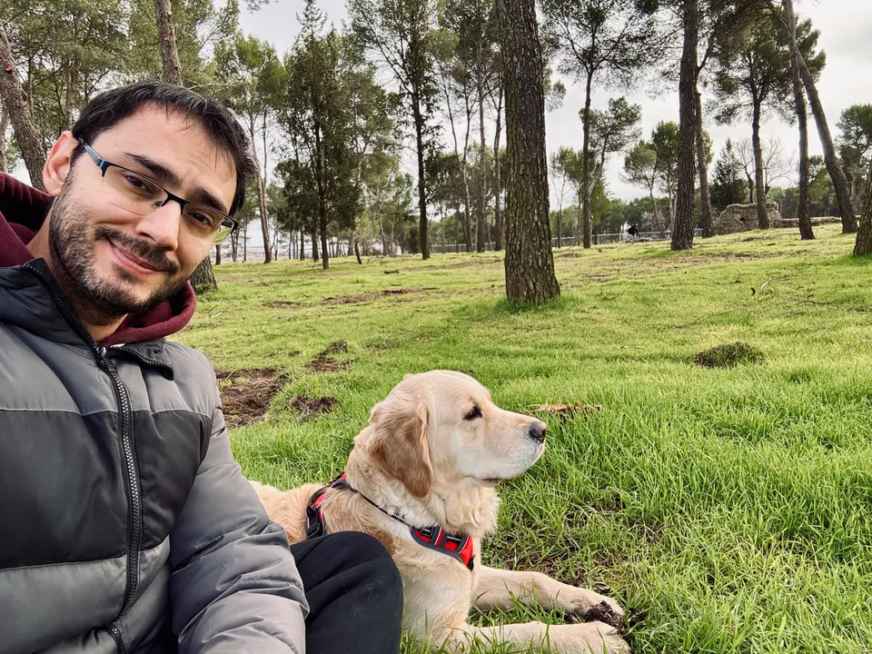 Luka and Kala sitting together on the grass in a pine grove.